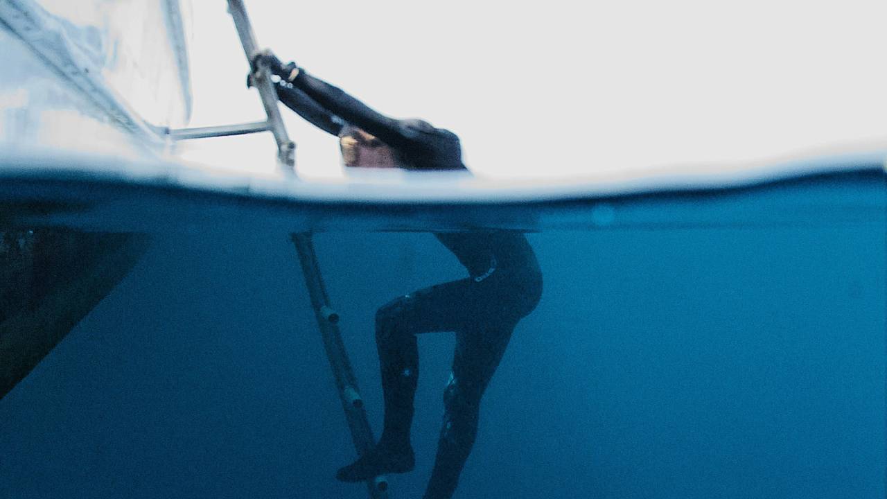 A diver climbing out of the sea and onto the boat 