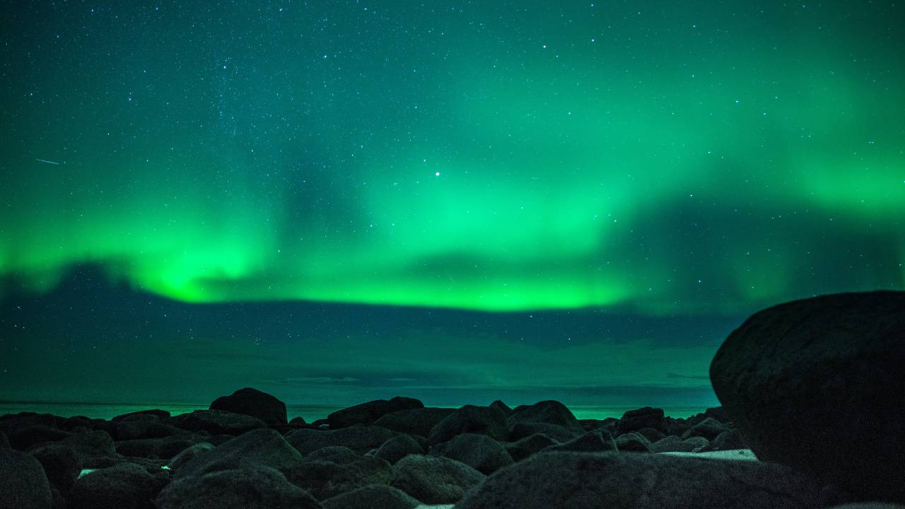 Aurora Borealis above a rocky seacoast at the sky lagoon