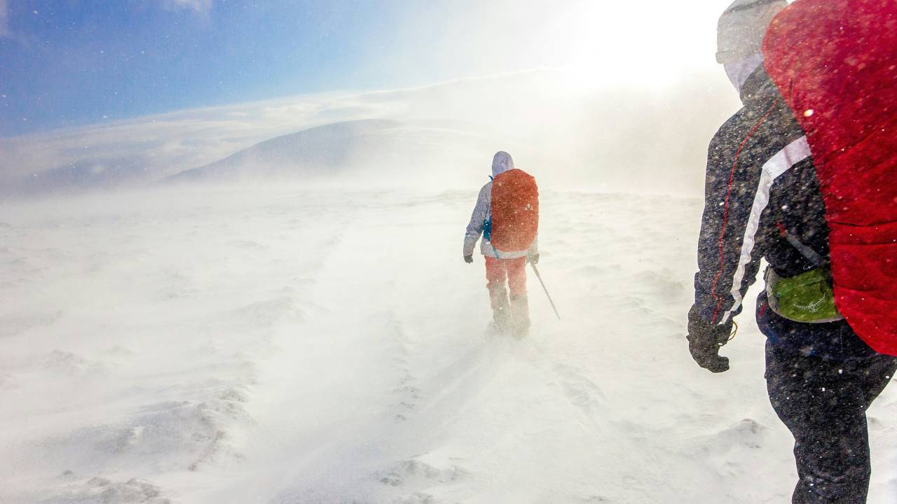 Two people hiking in a blizzard 
